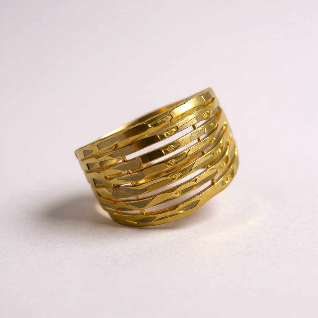 Gold ring with geometric design on a light gray background