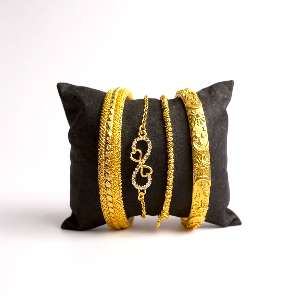 18k Gold-plated bracelets on a black pillow against a white background