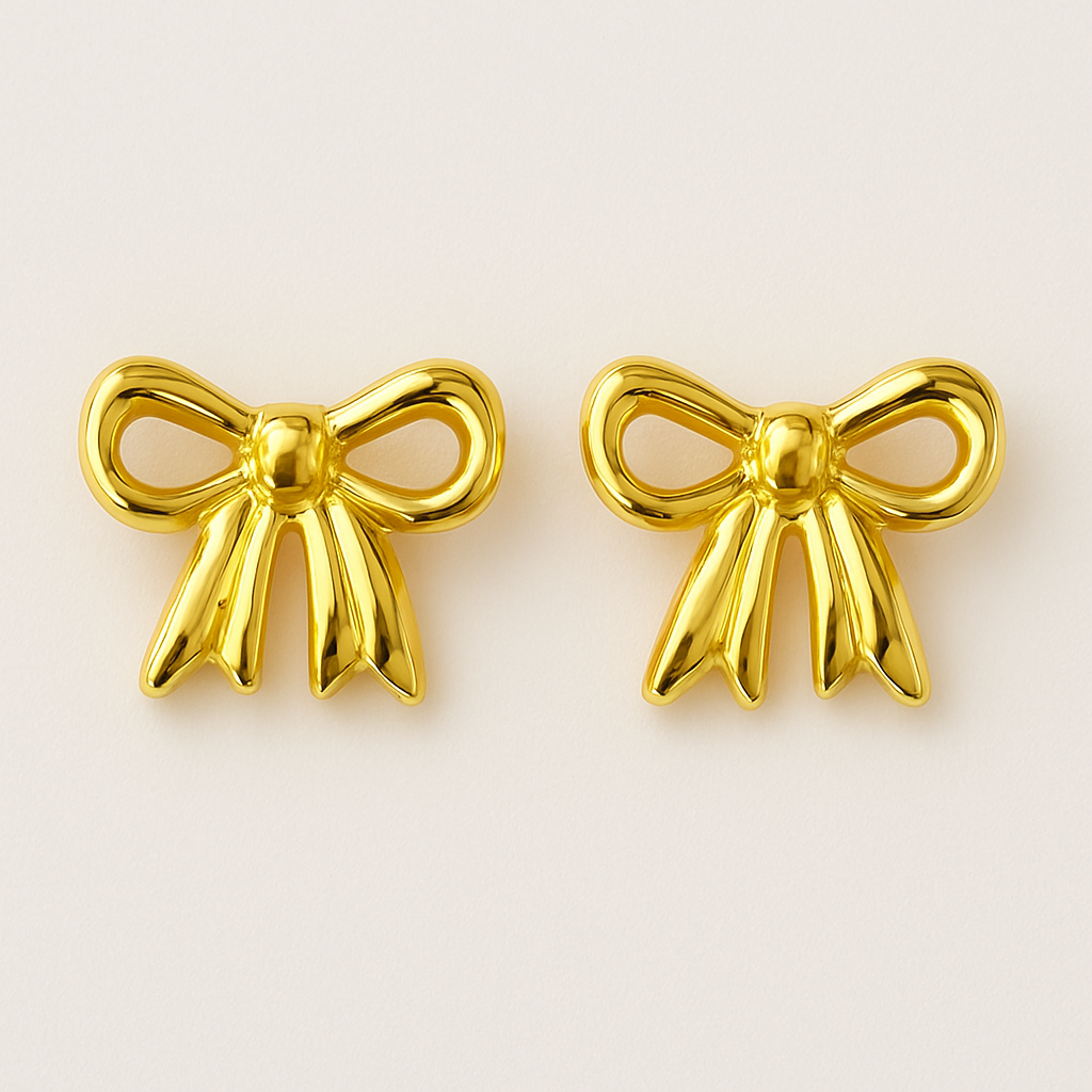Gold bow-shaped earrings on a beige background