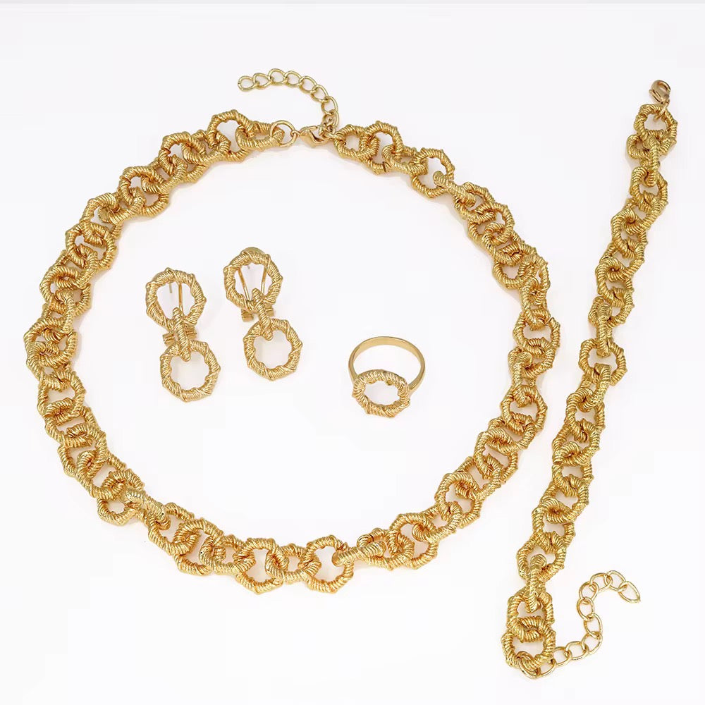 Gold jewelry set including necklace, earrings, bracelet and ring on a white background