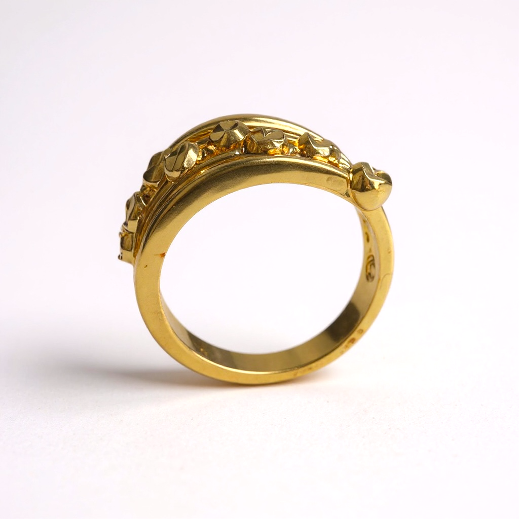 Gold ring with intricate design on a white background