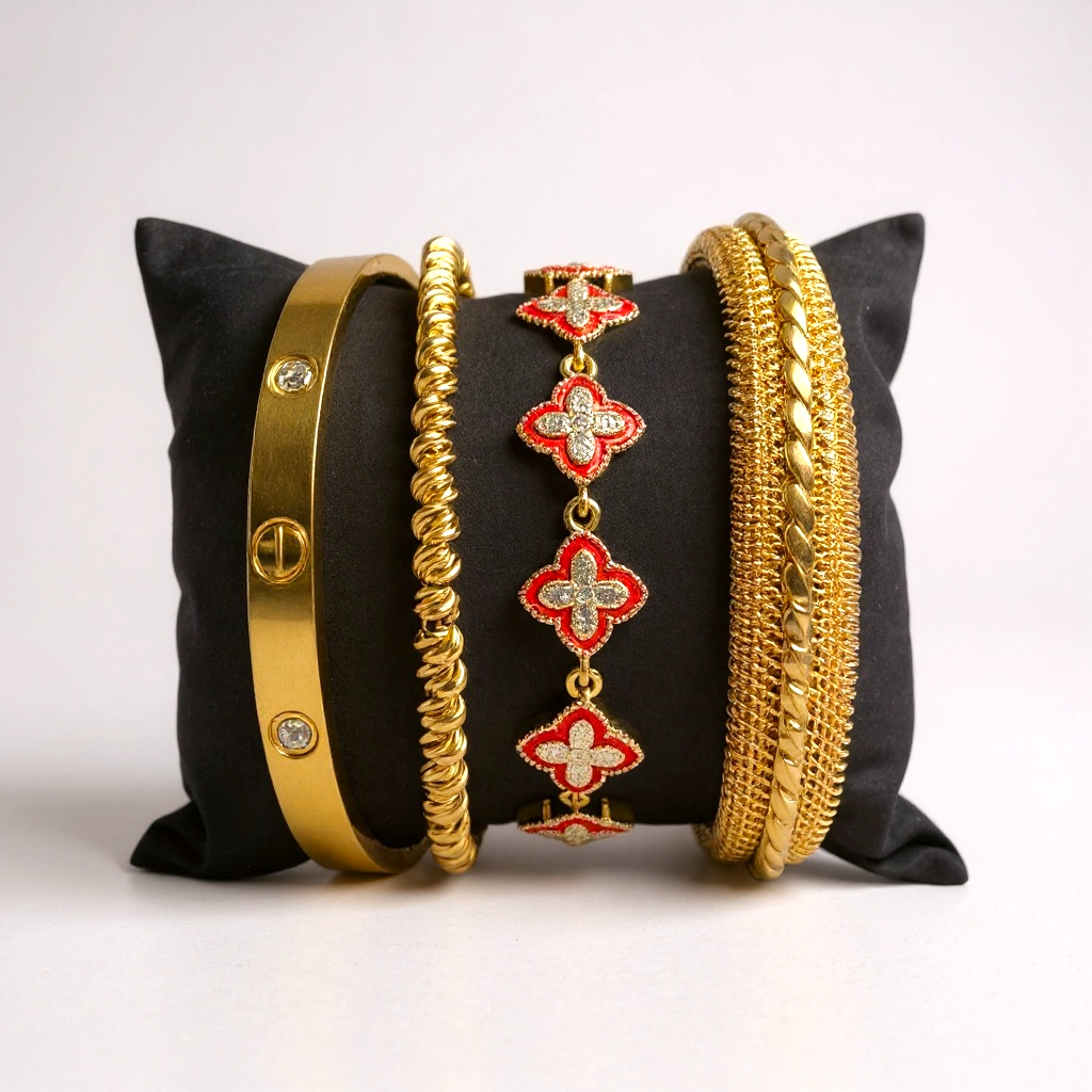 Set of gold and red jewelry on a black pillow with a white background