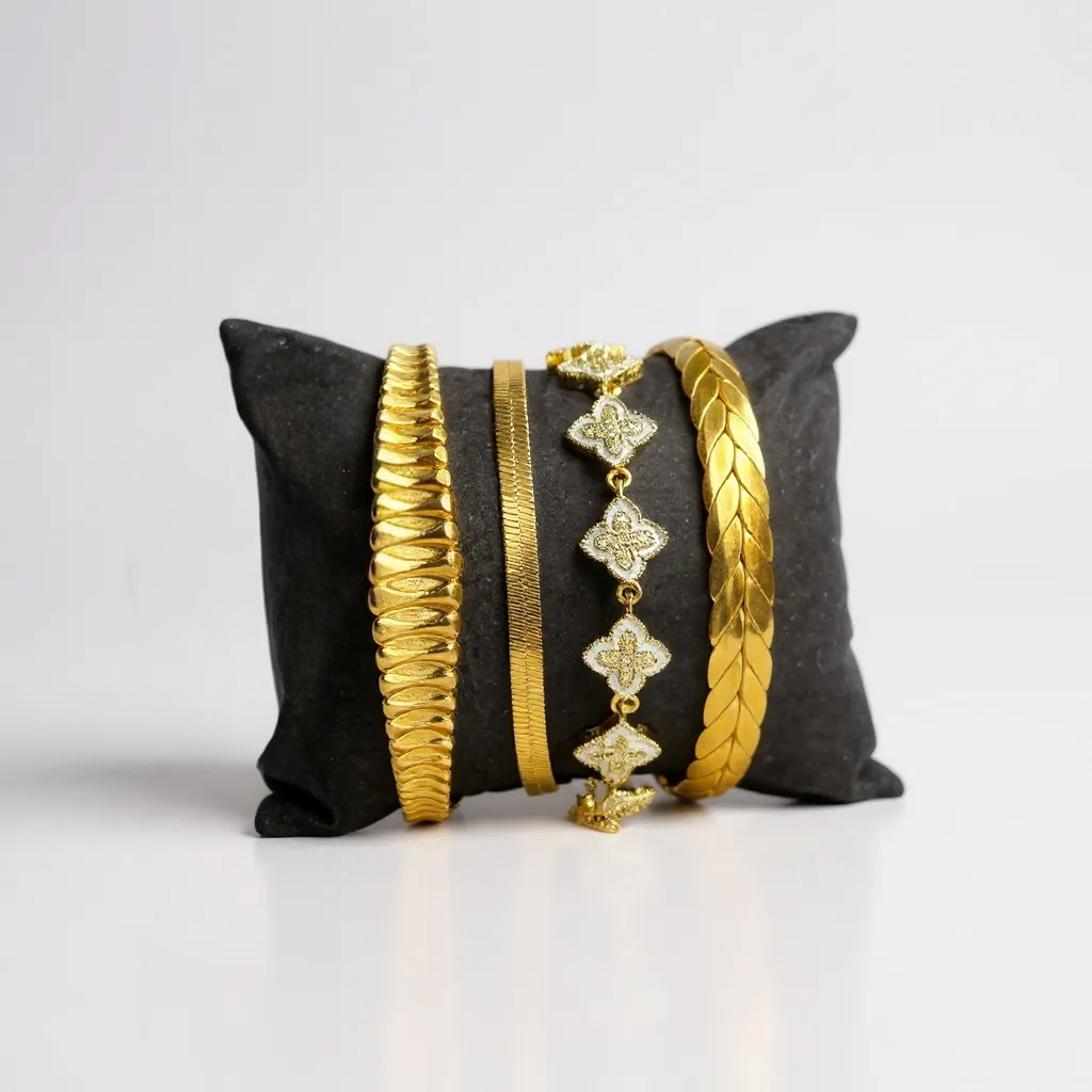 Gold bracelets on a black pillow against a white background
