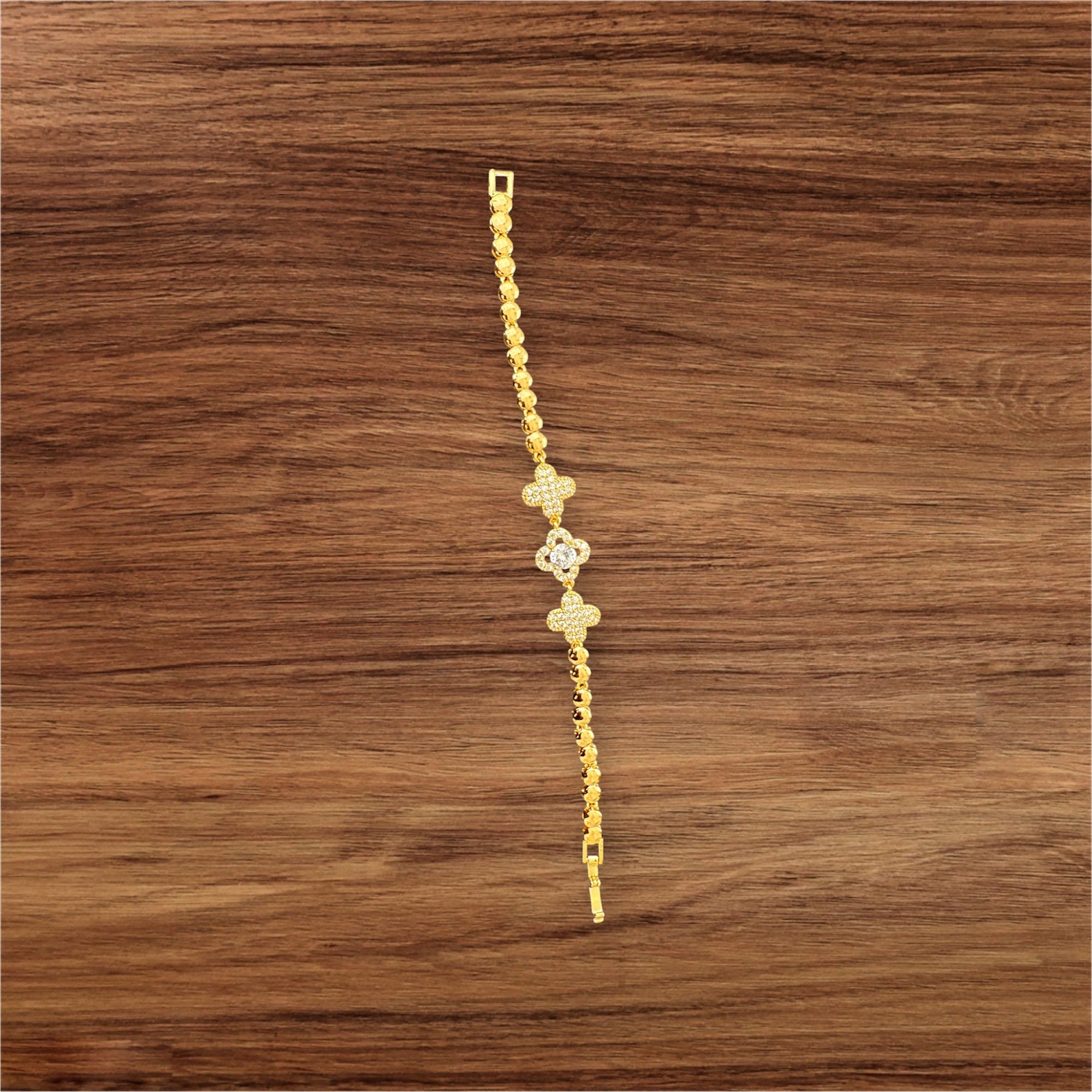Gold bracelet with floral designs on a wooden surface