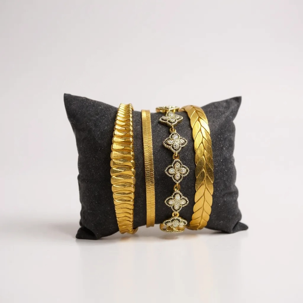 Gold bangles on a gray pillow against a white background