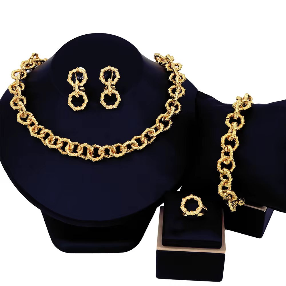 Gold chain necklace, earrings, and bracelet set on a black stand with a white background