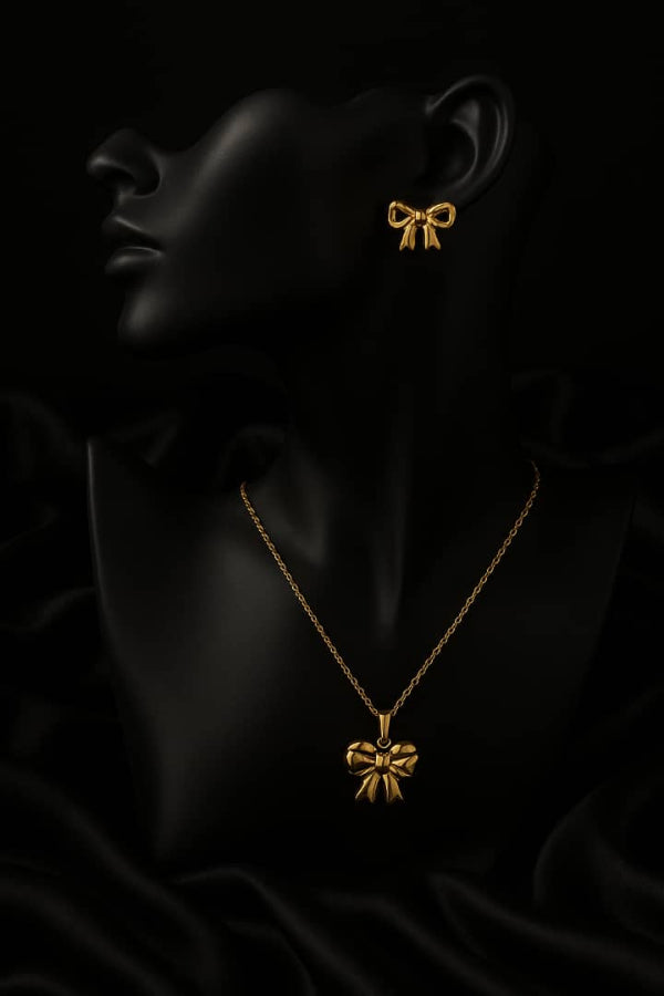 Gold bow-shaped necklace and earrings on a black mannequin with dark background