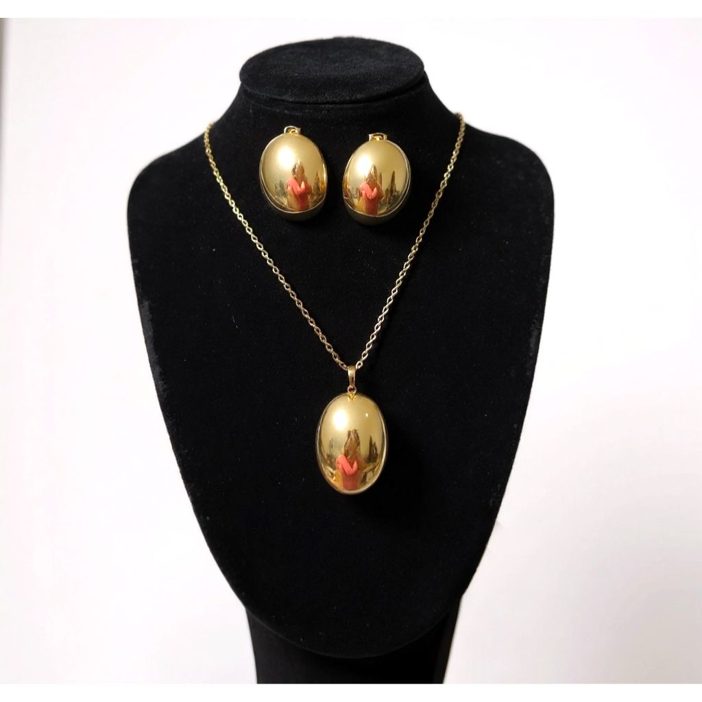 Gold necklace and earrings set on a black mannequin bust with a white background